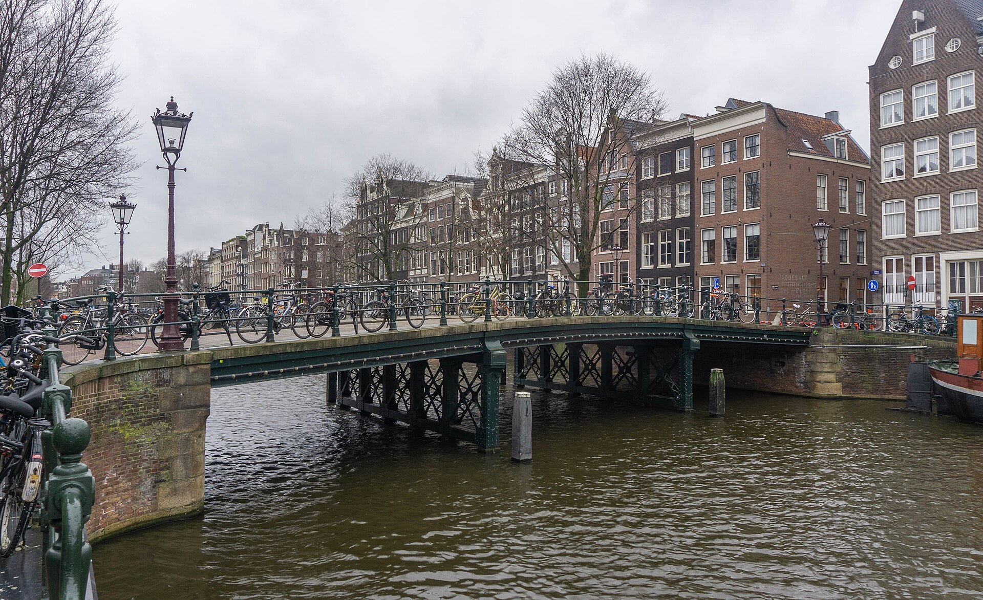A bridge lined with bicycles beside Amsterdam canal houses.